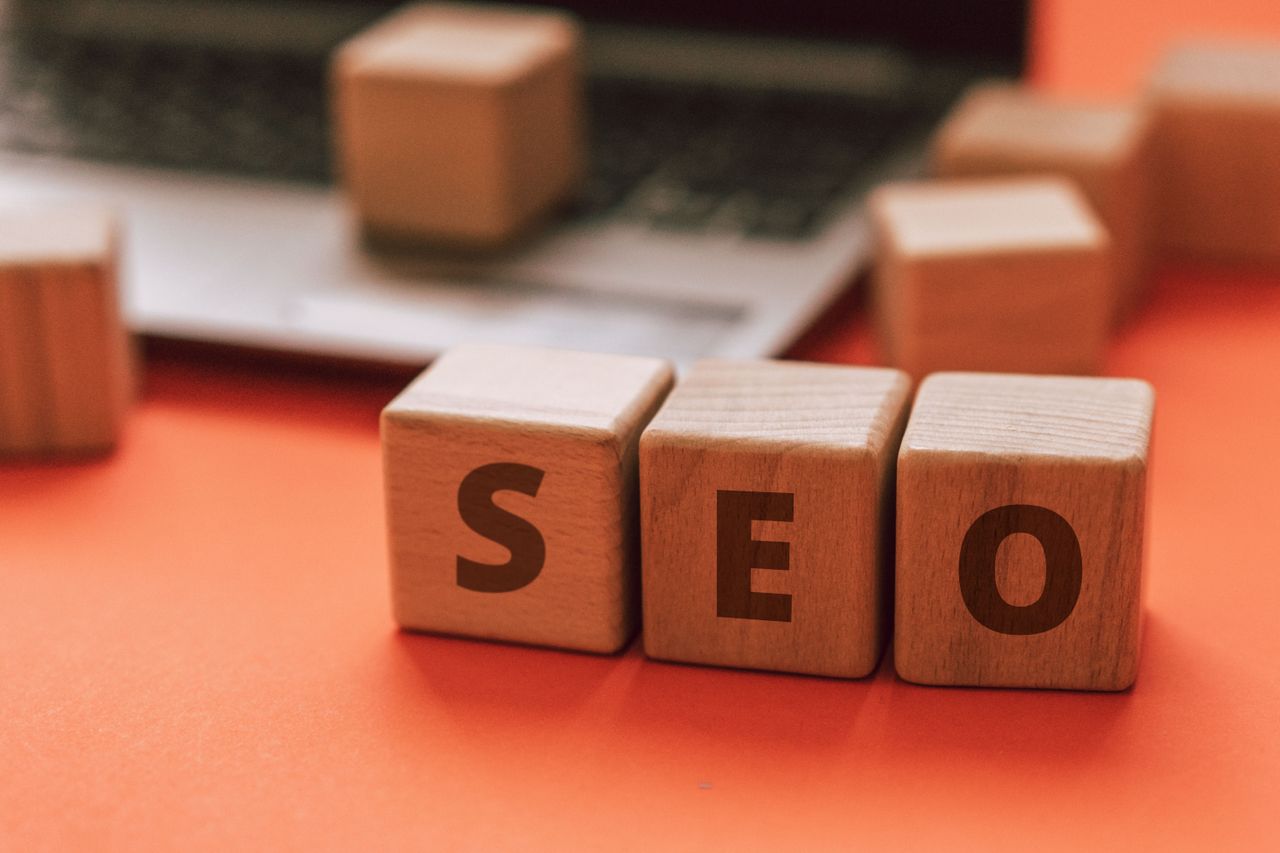 Des blocs en bois formant SEO sur le clavier d’un ordinateur portable illustrent des notions de marketing digital.